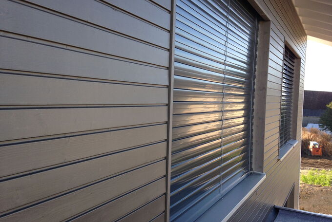 Gestrichene Holzschalung und dunkle Fensterstoren