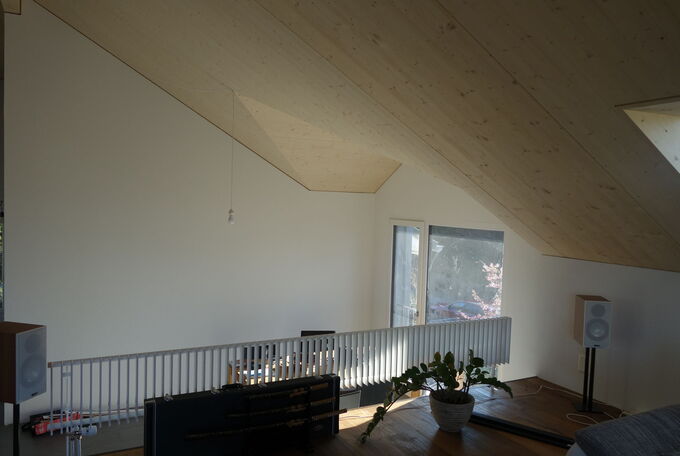 Als Raumtrenner des erhöhten Wohnzimmers dient ein schmaler, langer und stylischer Heizkörper über die ganze Raumlänge