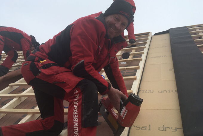 Ein Mitarbeiter bei der Monatage auf dem Dach, immer gut gelaunt und mit einem Lachen auf den Lippen