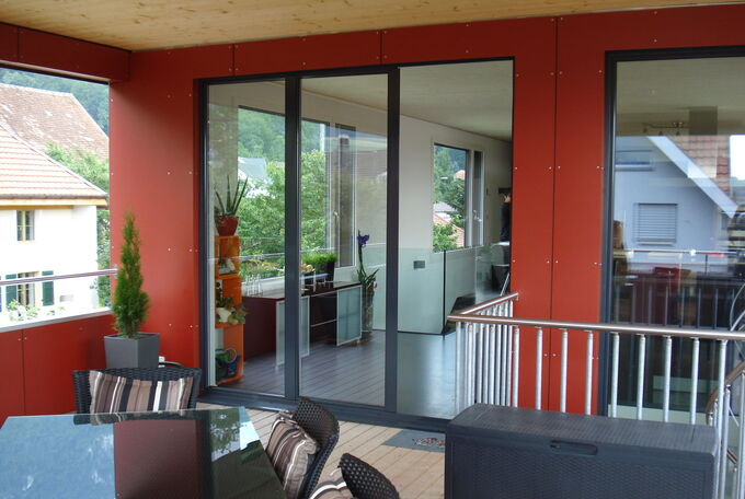 Gedeckter Sitzplatz im OG, Wendeltreppe ist rechts im Bild sichtbar, Stahlgeländer als Absturzsicherung, Holzboden bei Sitzplatz