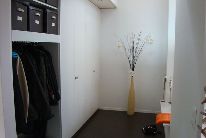 Eingangsbereich des rechteckigen Hauses, Einbau-Garderobe und offene Galerie ins OG, viel Tageslicht kommt durch die Verglasung über zwei Etagen in den Eingangsbereich