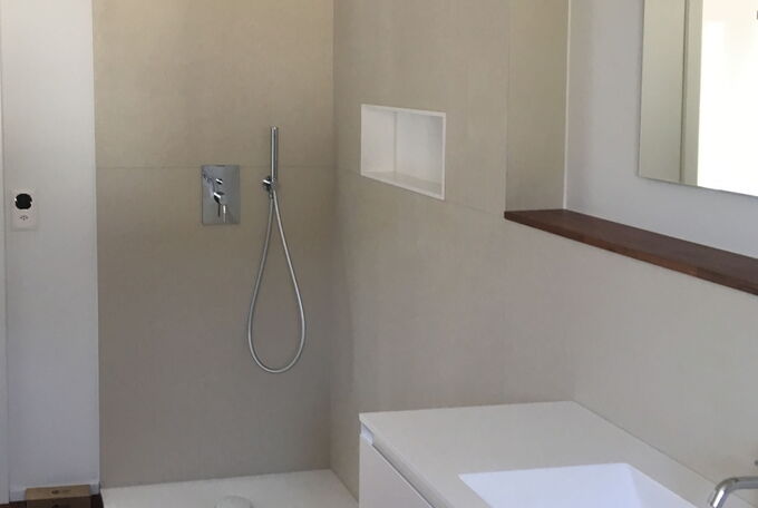 Umbau Badezimmer mit hellen Wandplatten, dunkler Parkettboden und grosser Dusche