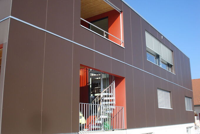 Rückseite des ins Haus integrieten Carports ist offen, mit Stahlgeländer abgeschlossen und zum gedeckten Sitzplatz im OG führt eine Wendeltreppe