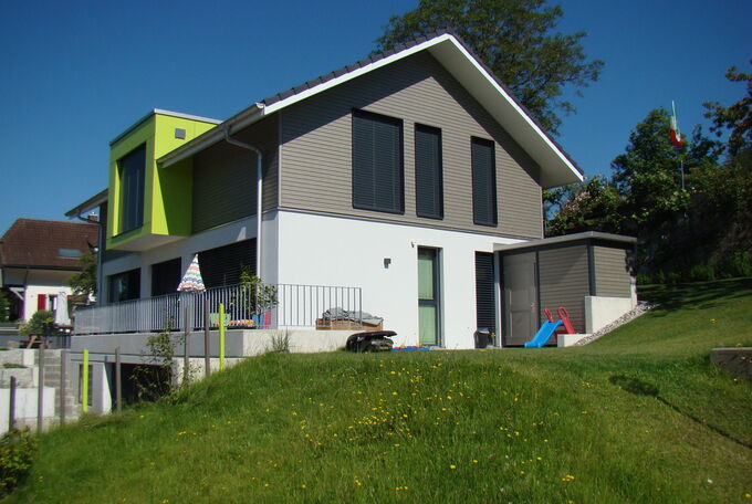 Einfamilienhaus mit Satteldach, Aussenwäne im EG verputzt, im OG mit hellgrauer Holzschalung verkleidet