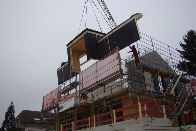 Dachelement mit integrierter Lukarne am Kran, wird auf Baustelle versetzt