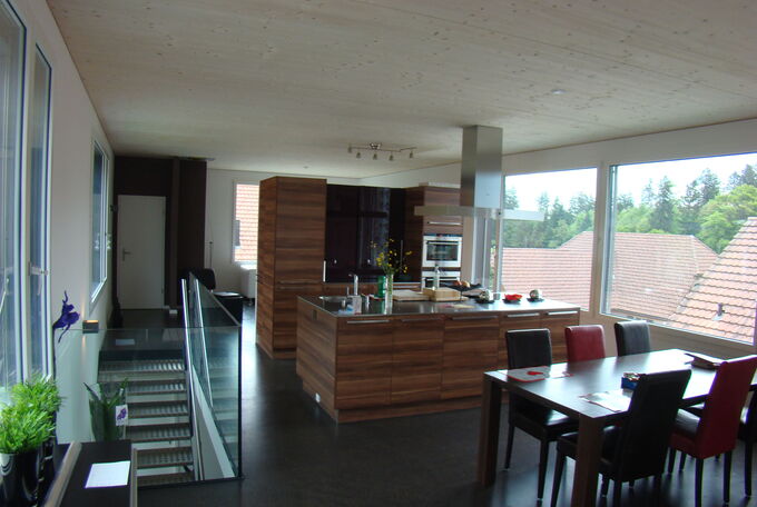 Wohnen, Kochen und Essen im Obergeschoss, Küche steht mittig im Raum und dient zugleich als Wohntrenner zwischen Essen und Wohnen