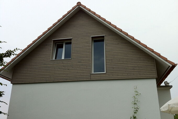 Ansicht der Rückseite des Hauses, Fassade des Obergeschosses mit grauer Holzschalung Erdgeschoss verputzt