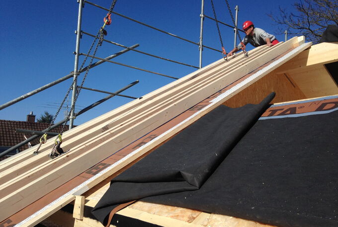 Satteldachelement wird mit Kran auf das Haus gehoben und millimetergenau montiert