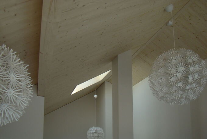 Das Dachfenster bringt viel Tageslicht ind Haus und erhellt auch die Treppe. Grosse, weisse Lampenschirme in Blütenoptik wurden an die hohe Decke montiert