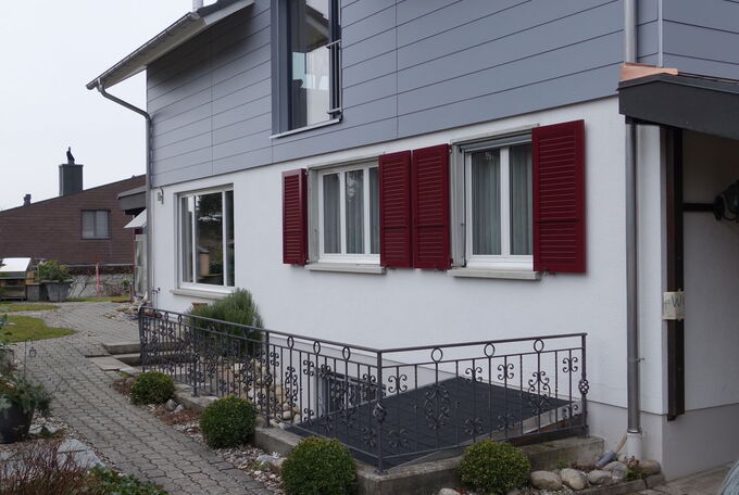 Aufstockung mit komplett ausgebauter Wohnung, Fassadenansicht mit hellgrauen Vollkernplatten verkleidet