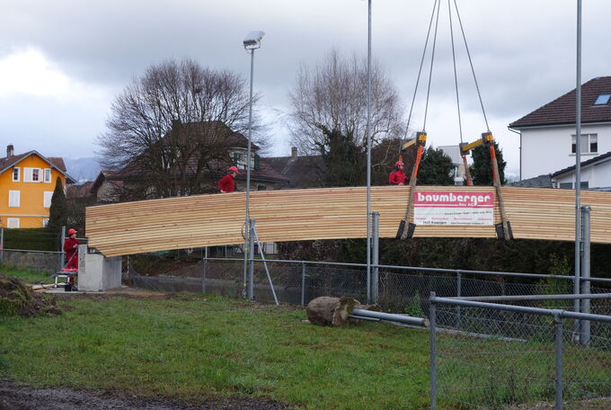 Holzbrücke hängt in den Krangurten und schwebt durch die Luft