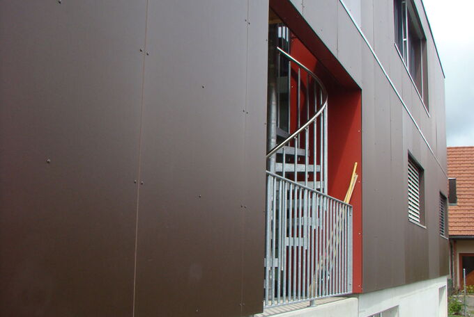 Rückseite des ins Haus integrieten Carports ist offen, mit Stahlgeländer abgeschlossen und zum gedeckten Sitzplatz im OG führt eine Wendeltreppe