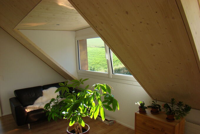 Innenansicht Flachdachlukarne mit grossen Fenstern, Parkettboden und hellem Holz als Deckenverkleidung